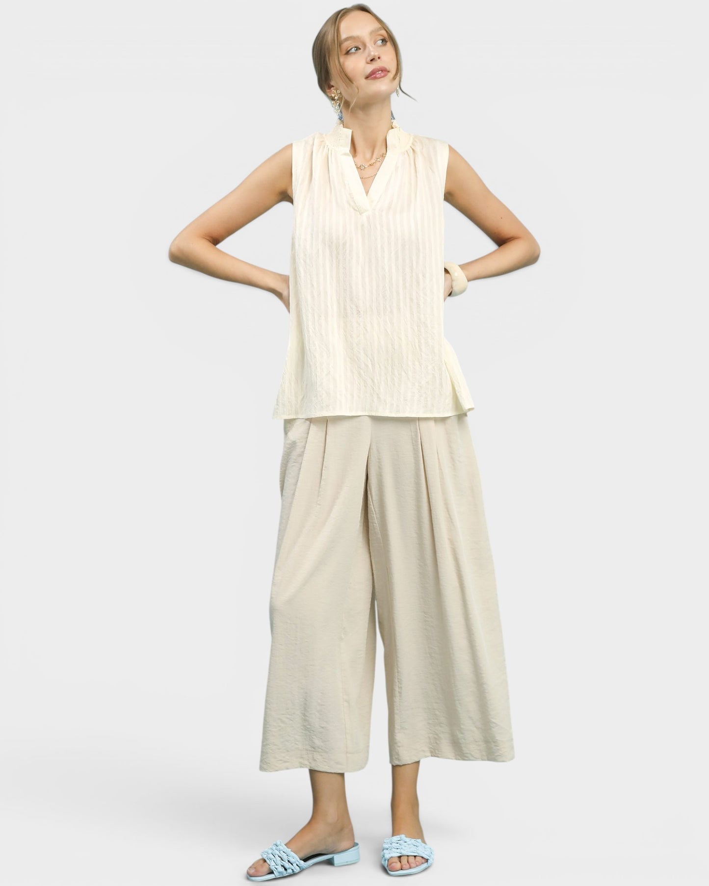 Woman wearing a sleeveless top and wide-leg pants on a white background
