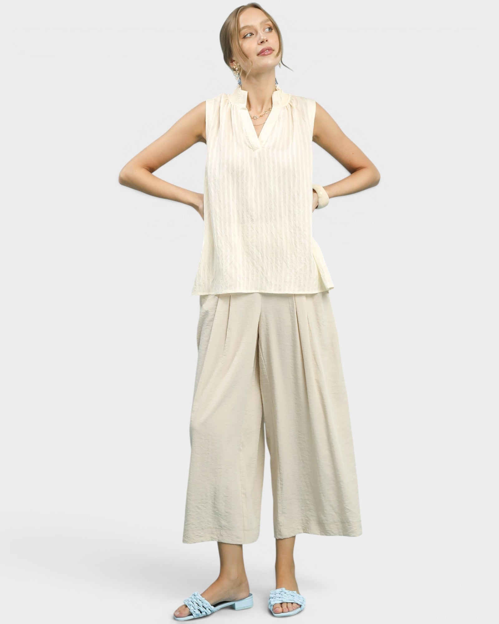 Woman wearing a sleeveless top and wide-leg pants on a white background