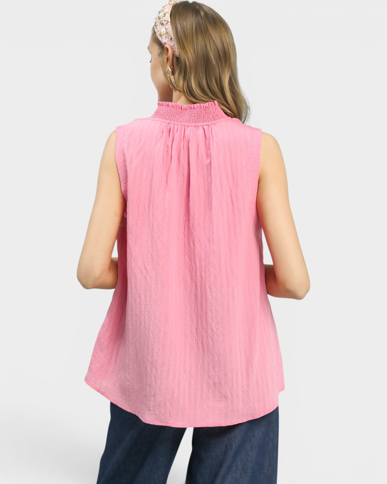 Woman wearing a pink sleeveless top with a white background