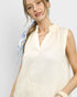 Woman wearing a white sleeveless top with a blue patterned scarf around her neck on a light gray background