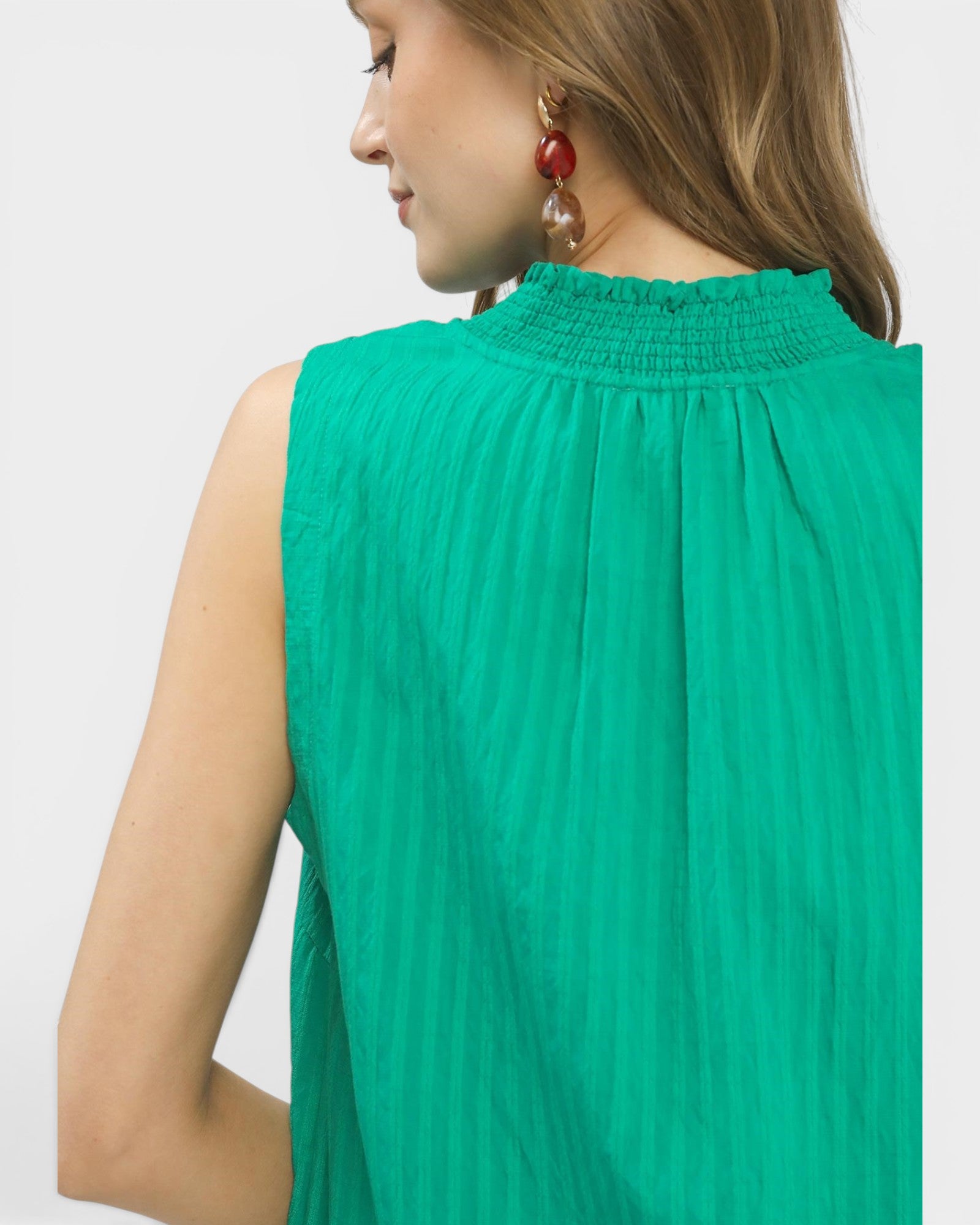 Green sleeveless top worn by a person on a white background