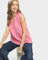 Woman wearing a pink sleeveless top and blue pants on a white background