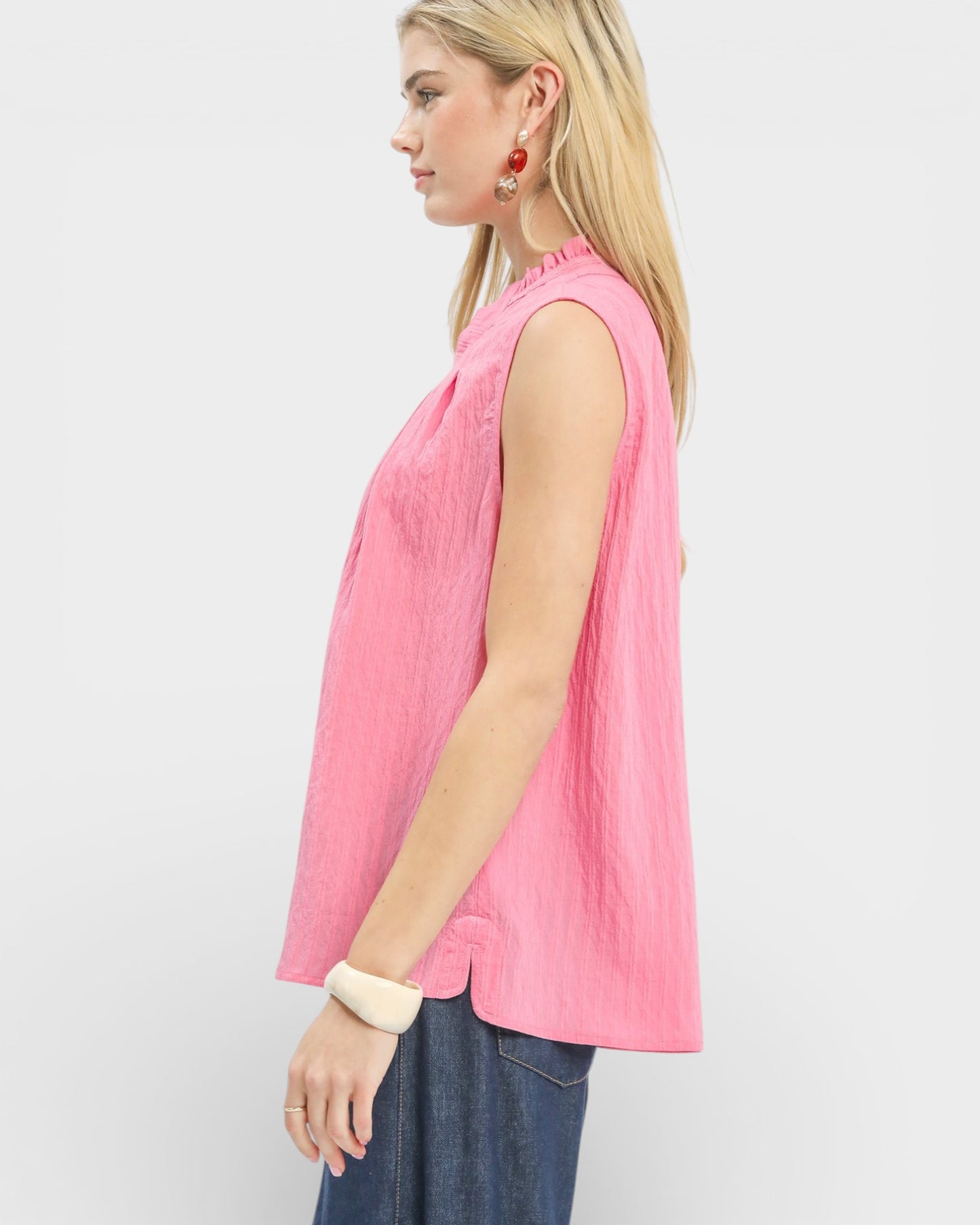 Woman wearing a pink sleeveless top against a white background