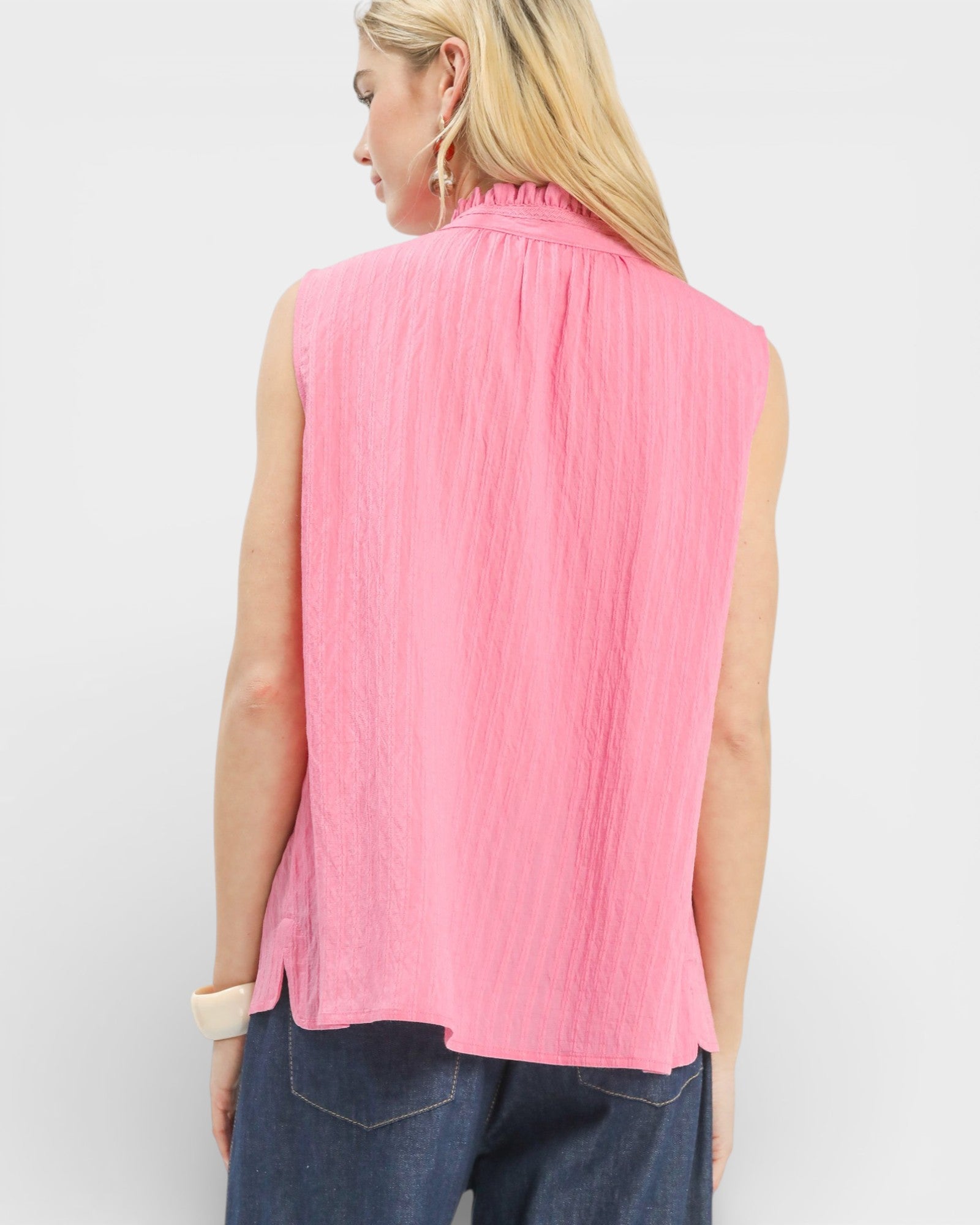 Woman wearing a pink sleeveless top against a white background