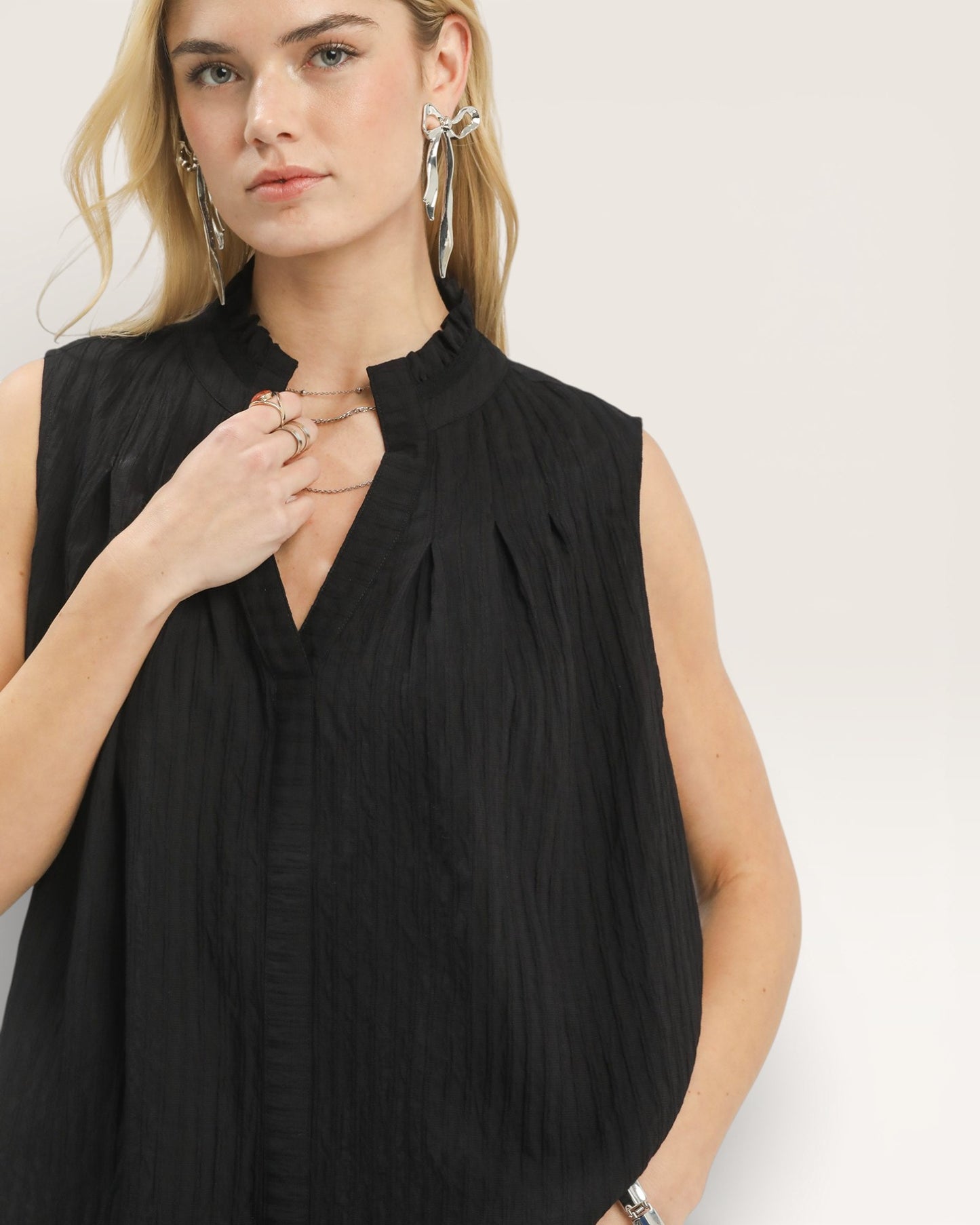 Woman wearing a black sleeveless top against a plain background