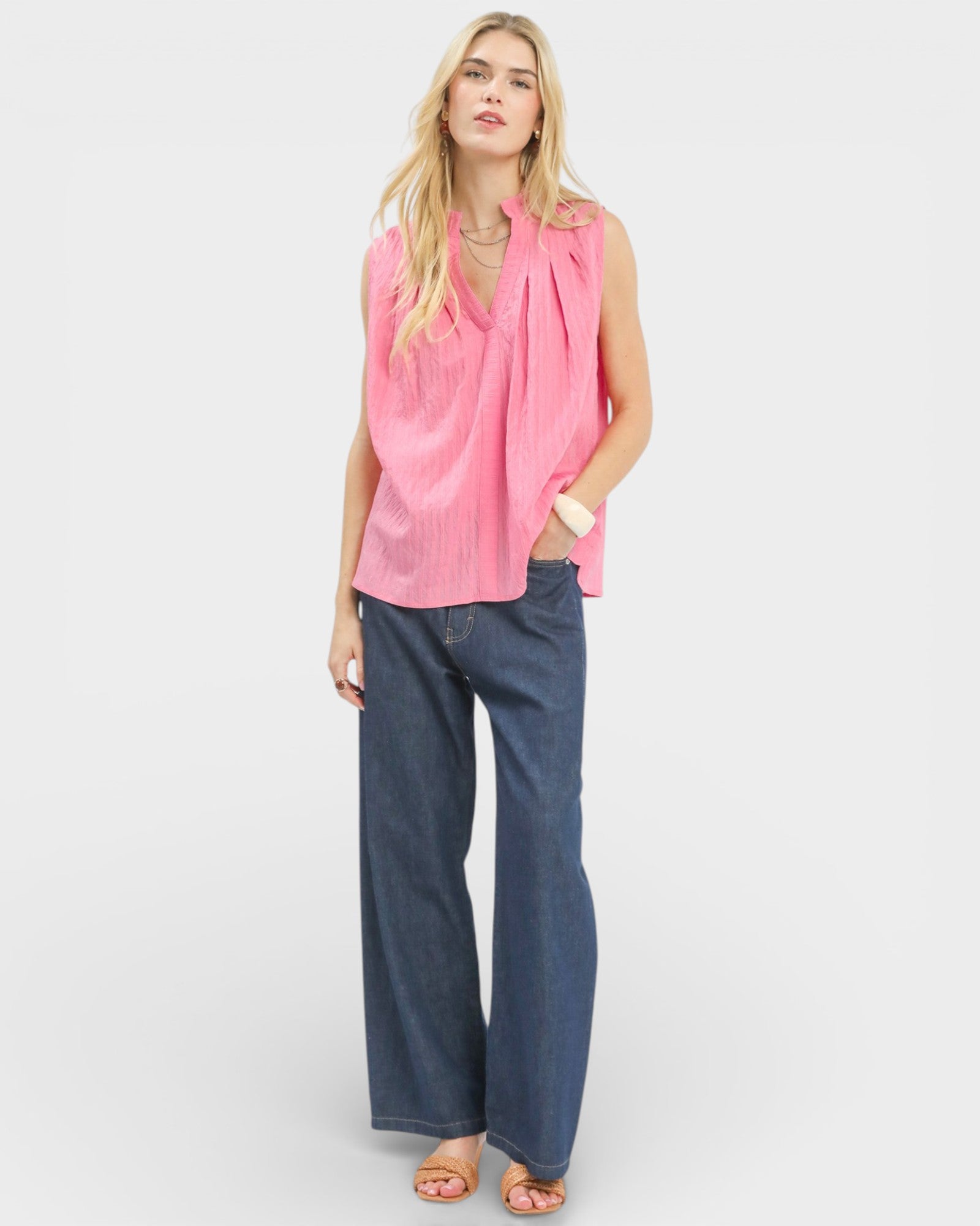 Woman wearing a pink sleeveless top and blue jeans on a white background