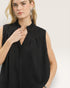 Woman wearing a black sleeveless top against a plain background