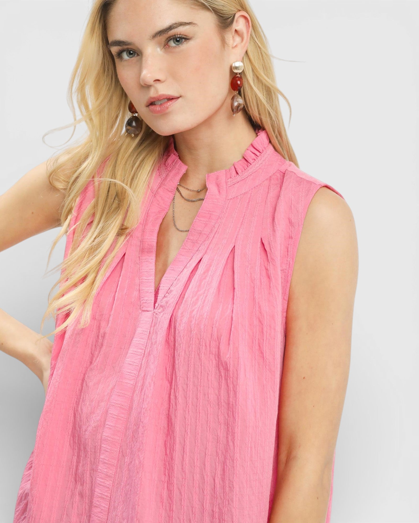Woman wearing a pink sleeveless top against a plain background