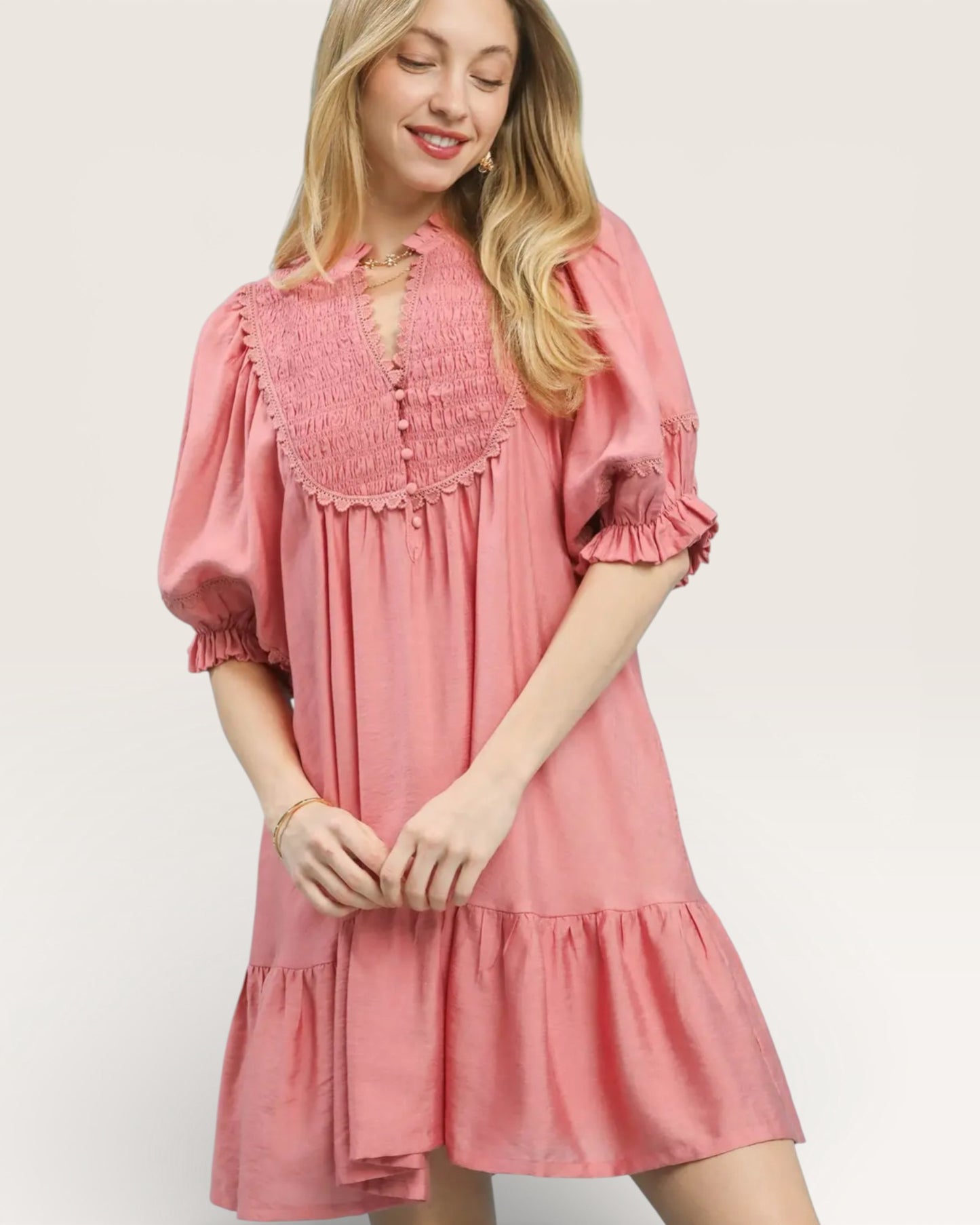 Woman wearing a pink dress with ruffled sleeves and bottom hem on a white background