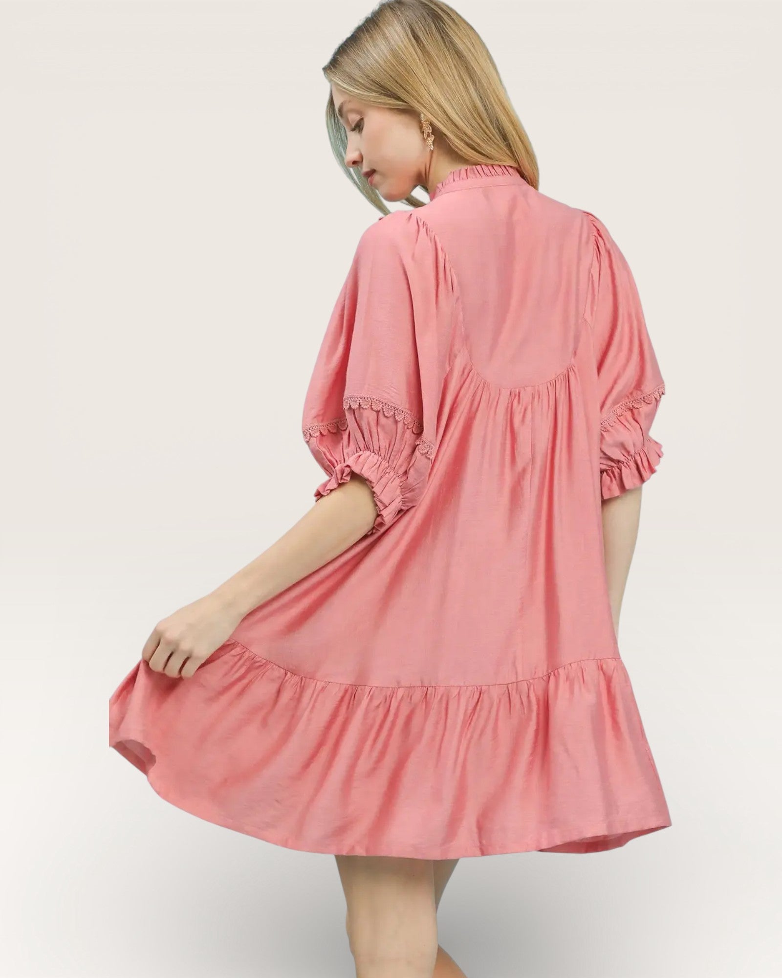 Woman wearing a pink dress with ruffled sleeves on a white background