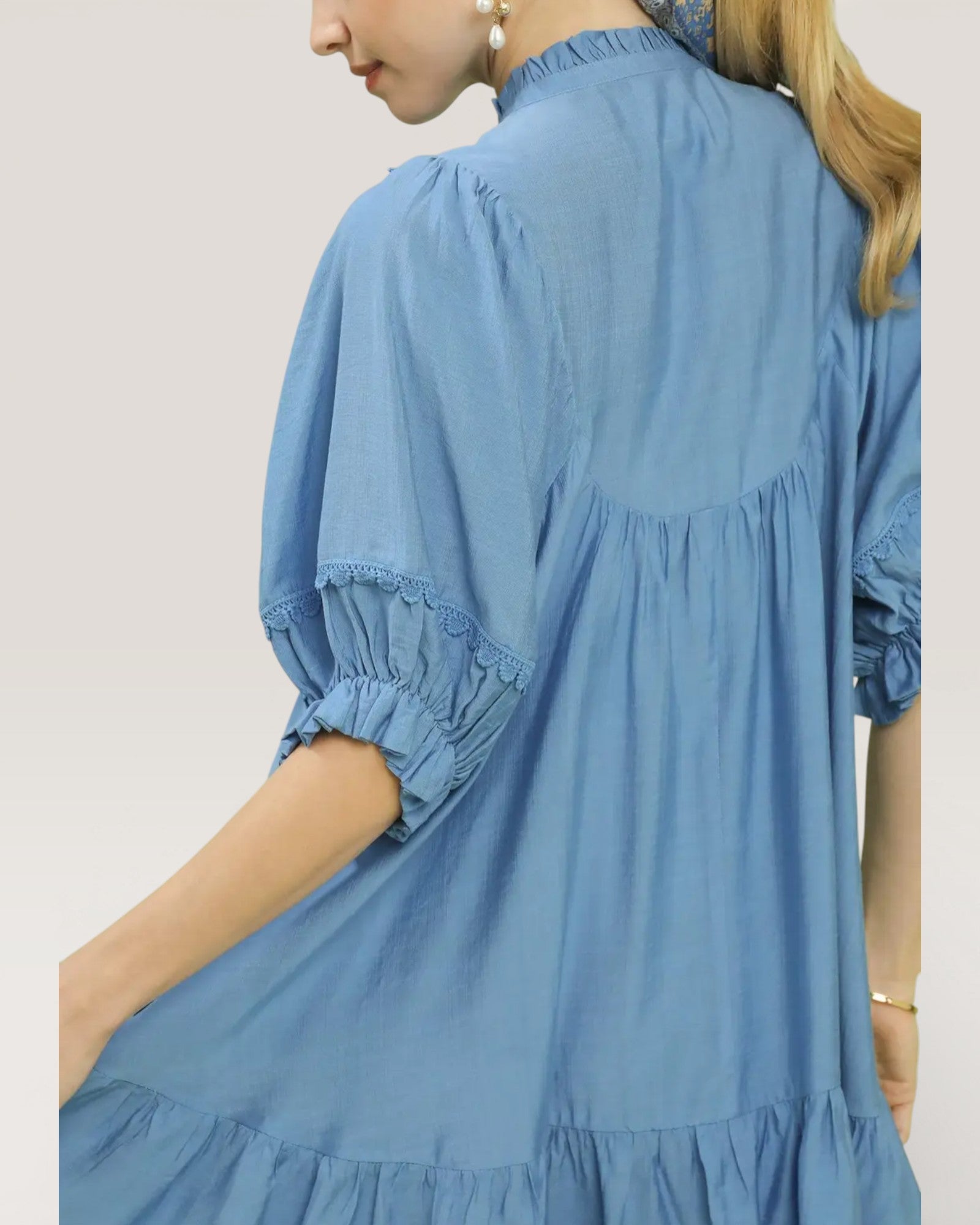 Blue dress with ruffled sleeves and bottom on a plain background