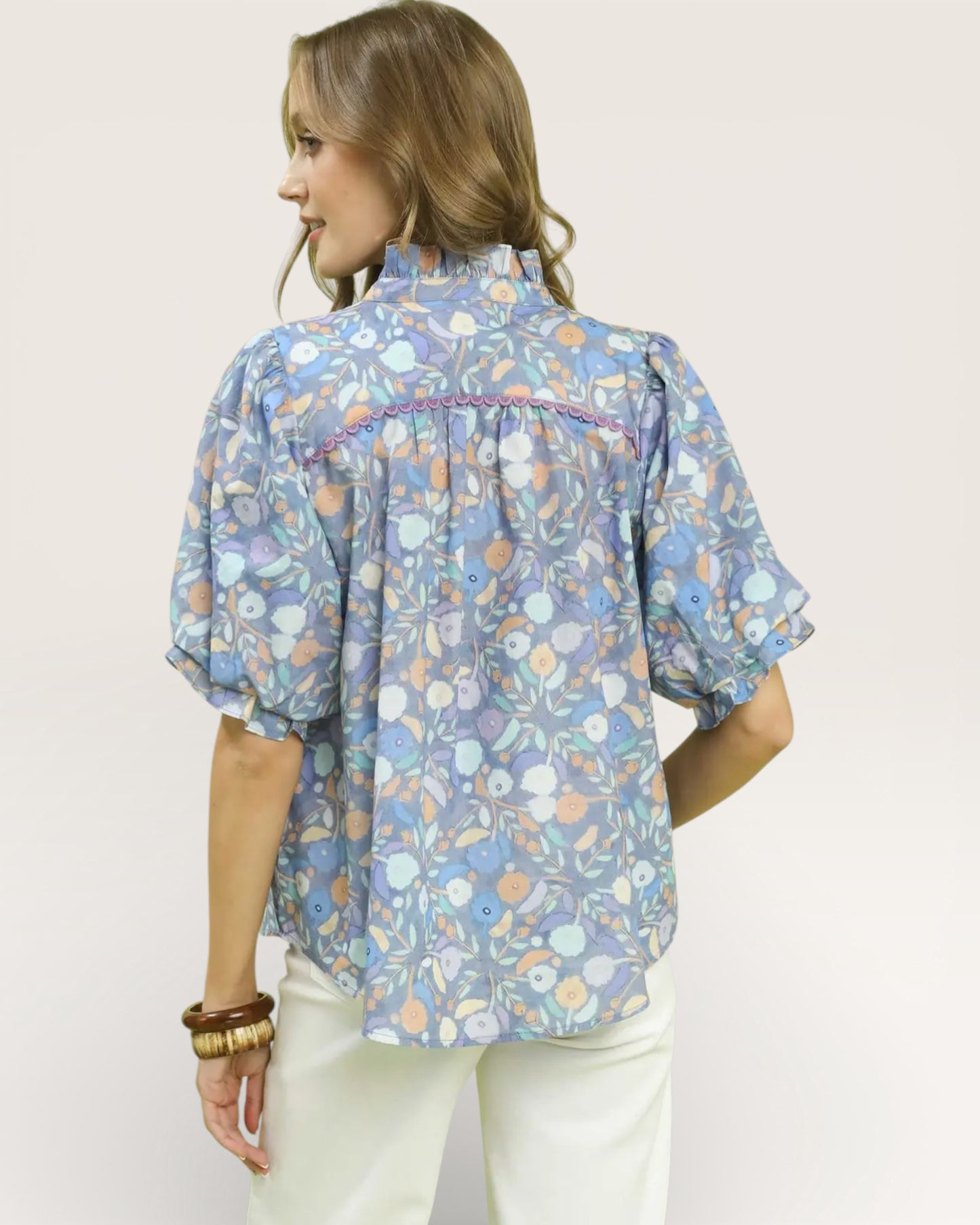 Woman wearing a floral patterned blouse against a plain background