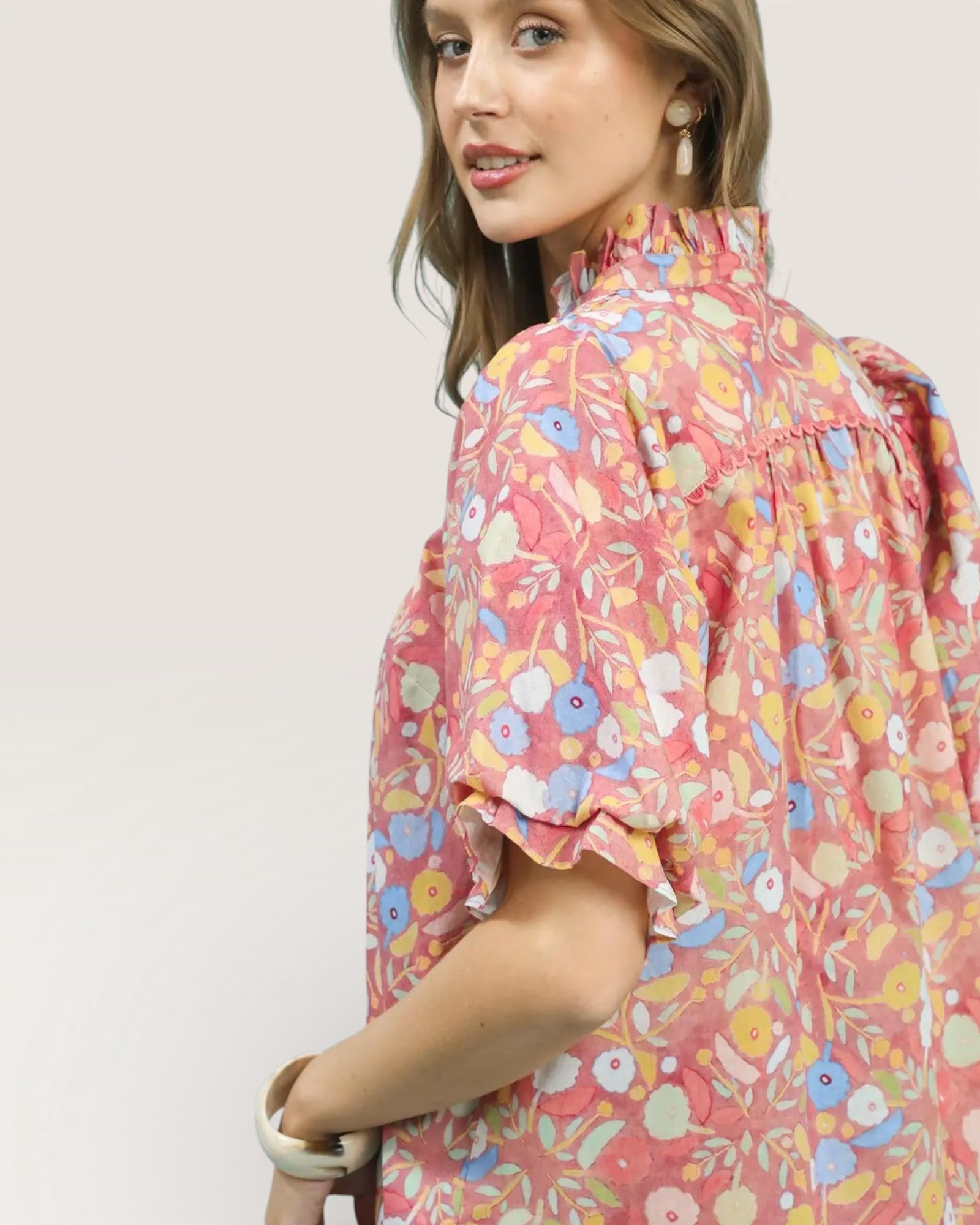 Woman wearing a colorful floral dress against a plain background