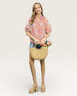 Woman holding a woven bag with flowers against a plain background