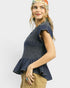 Woman wearing a denim peplum top and beige pants on a white background