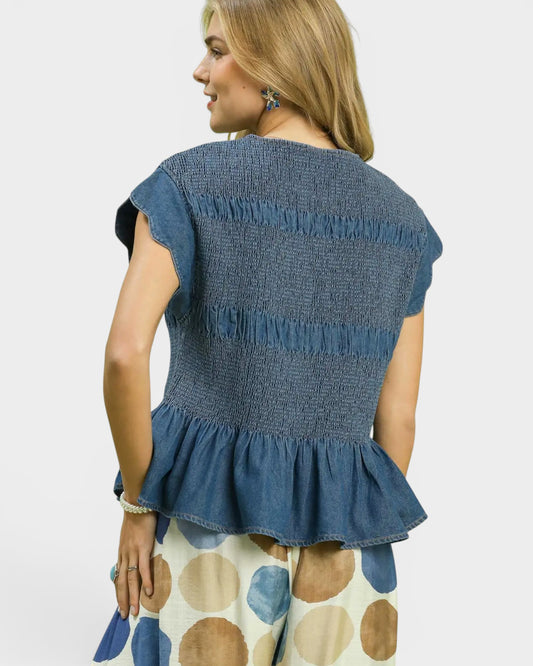 Woman wearing a blue denim top with a plain background