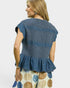 Woman wearing a blue denim top with a plain background
