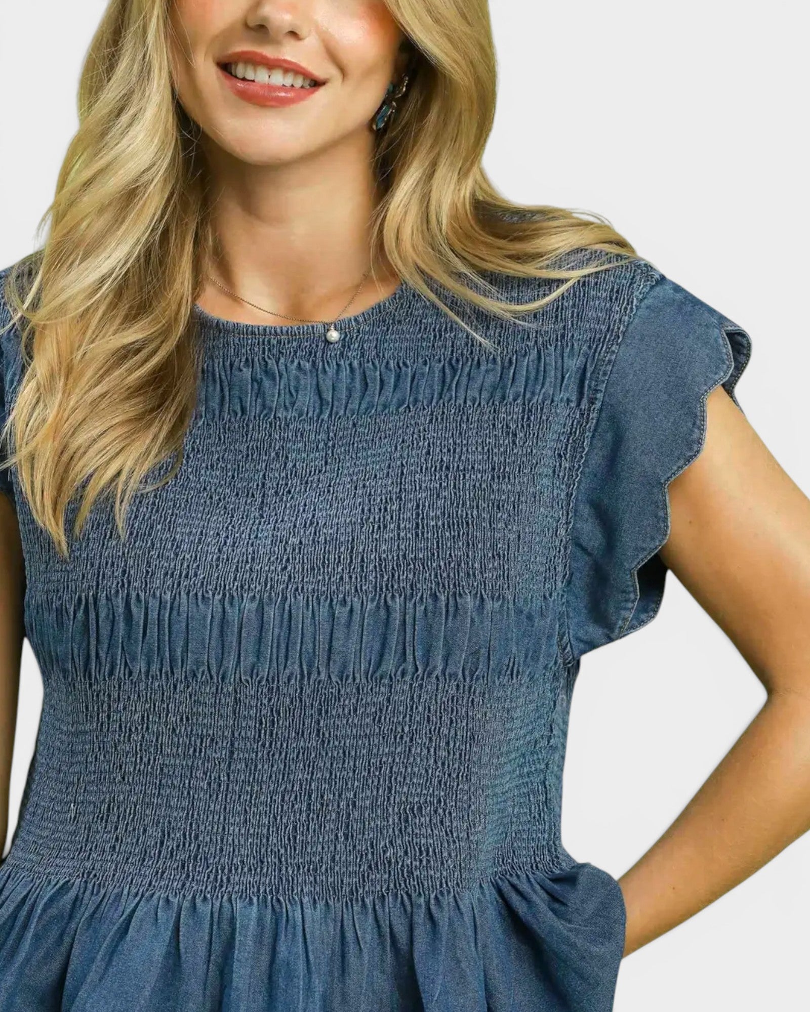 Woman wearing a blue smocked dress on a white background
