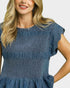Woman wearing a blue smocked dress on a white background