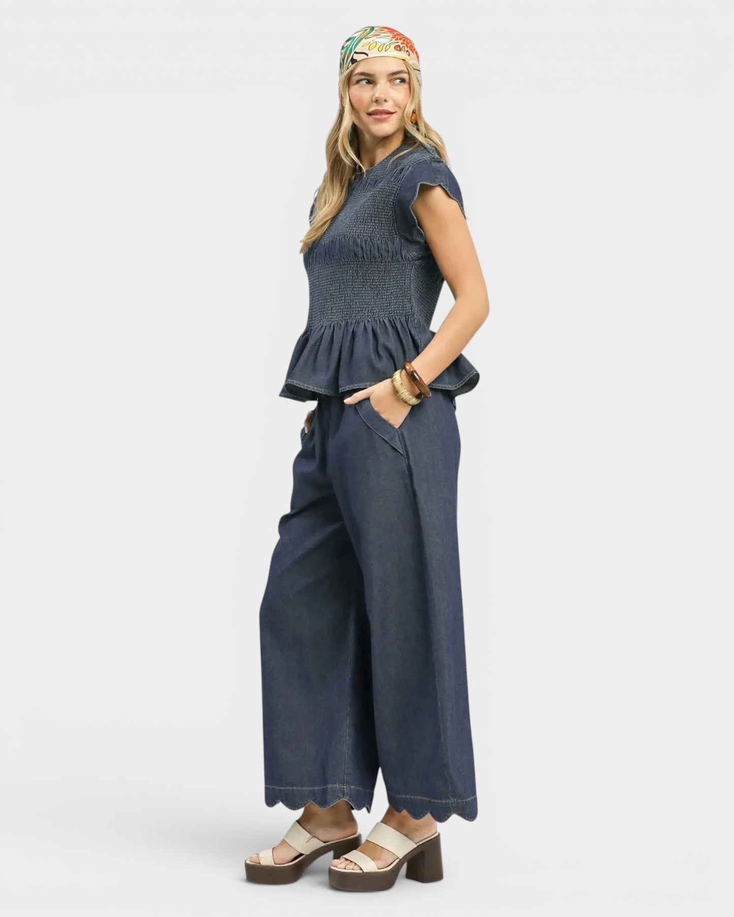 Woman wearing a blue top and wide-leg pants on a white background