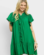Woman wearing a green dress with ruffled details on a white background