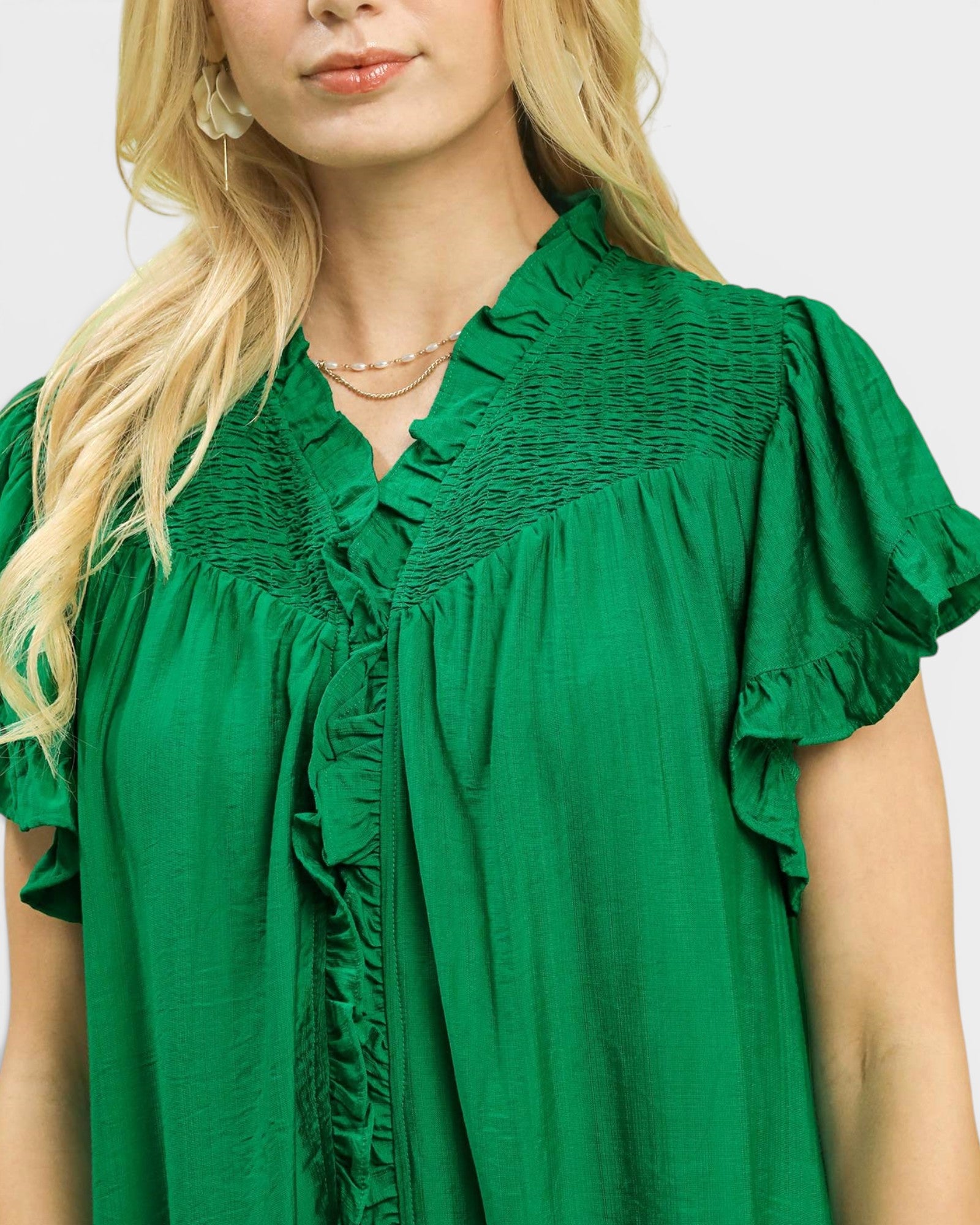 Green dress with ruffled details worn by a person on a white background