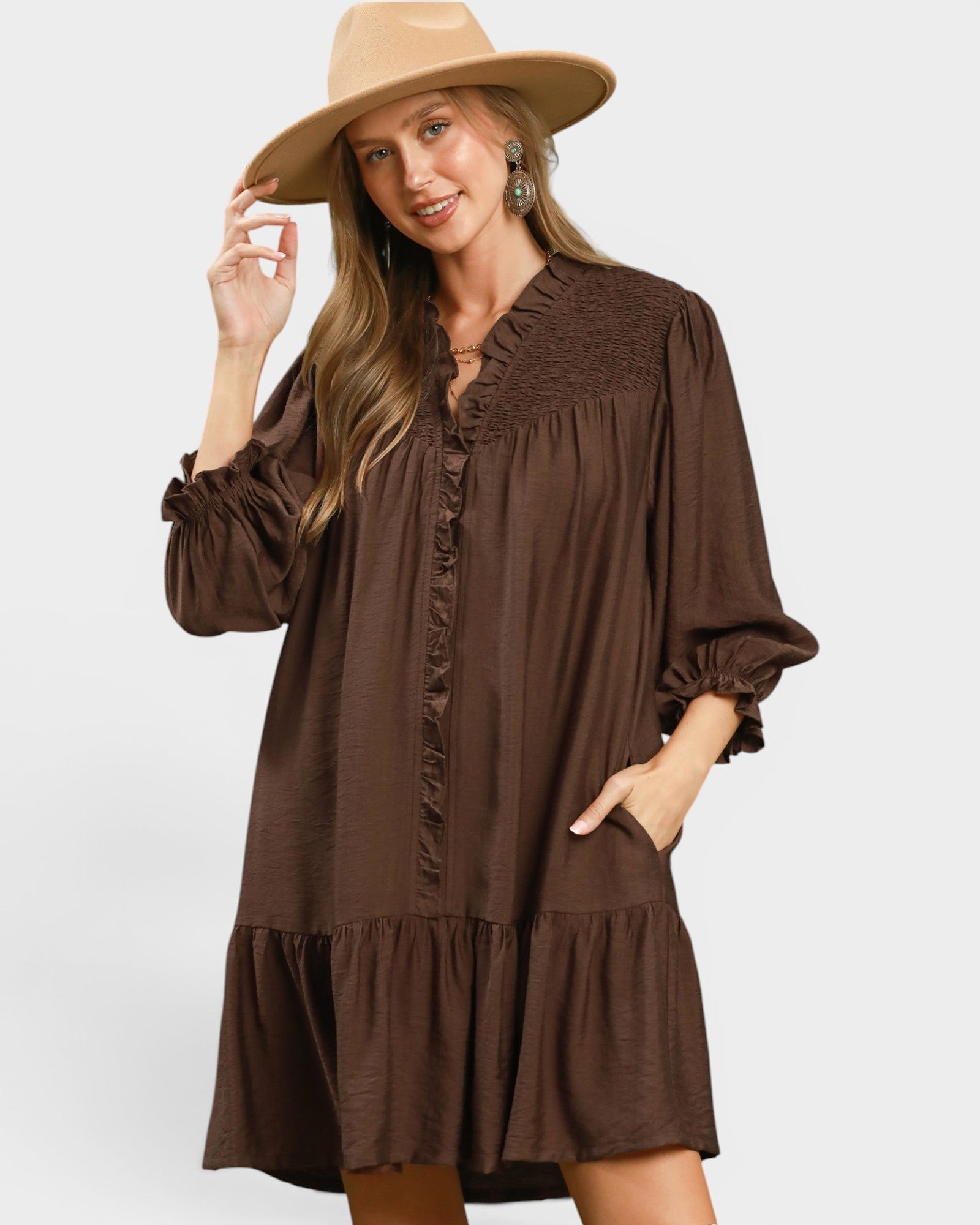 Woman wearing a brown dress and beige hat on a white background