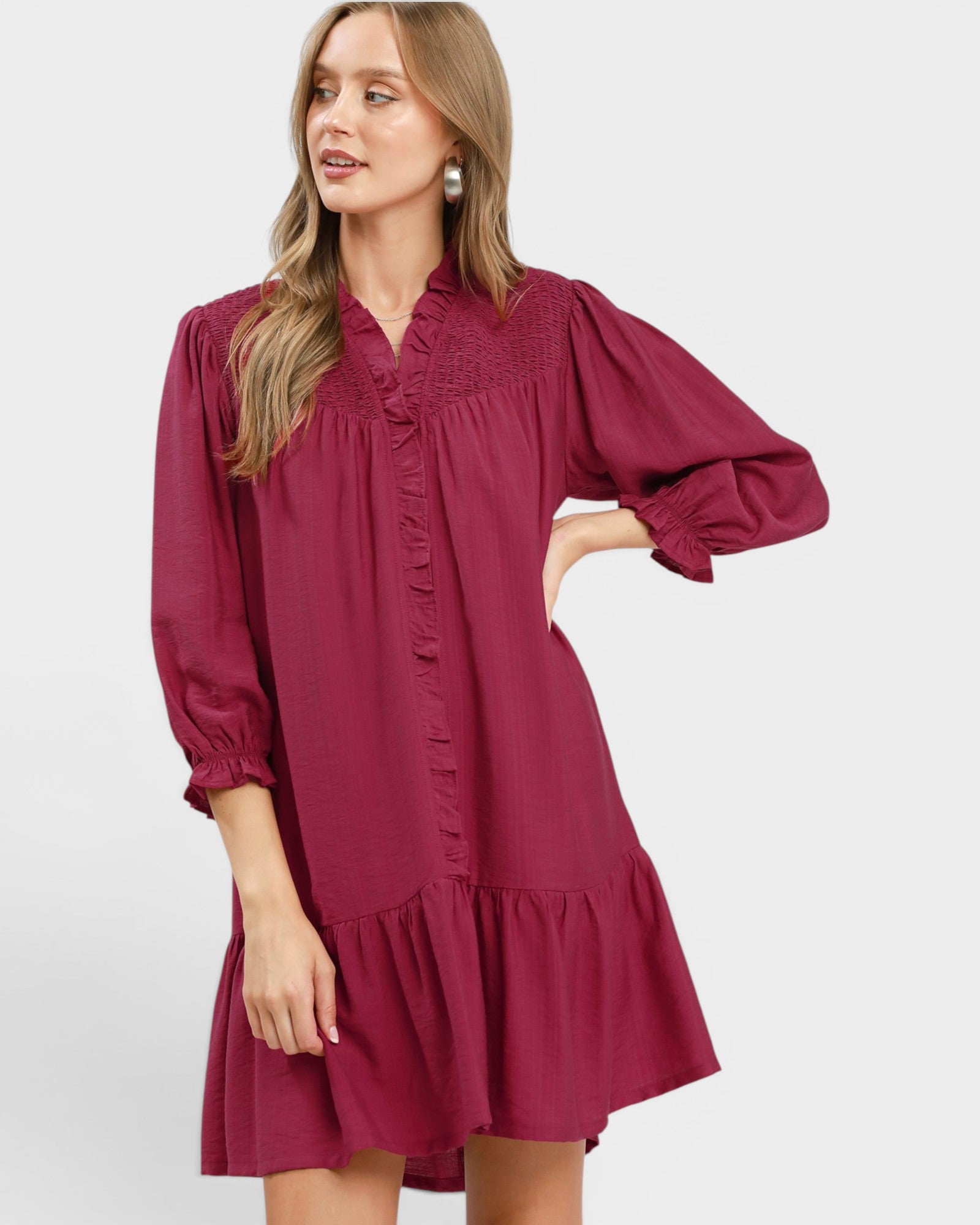 Woman wearing a burgundy dress with long sleeves on a white background