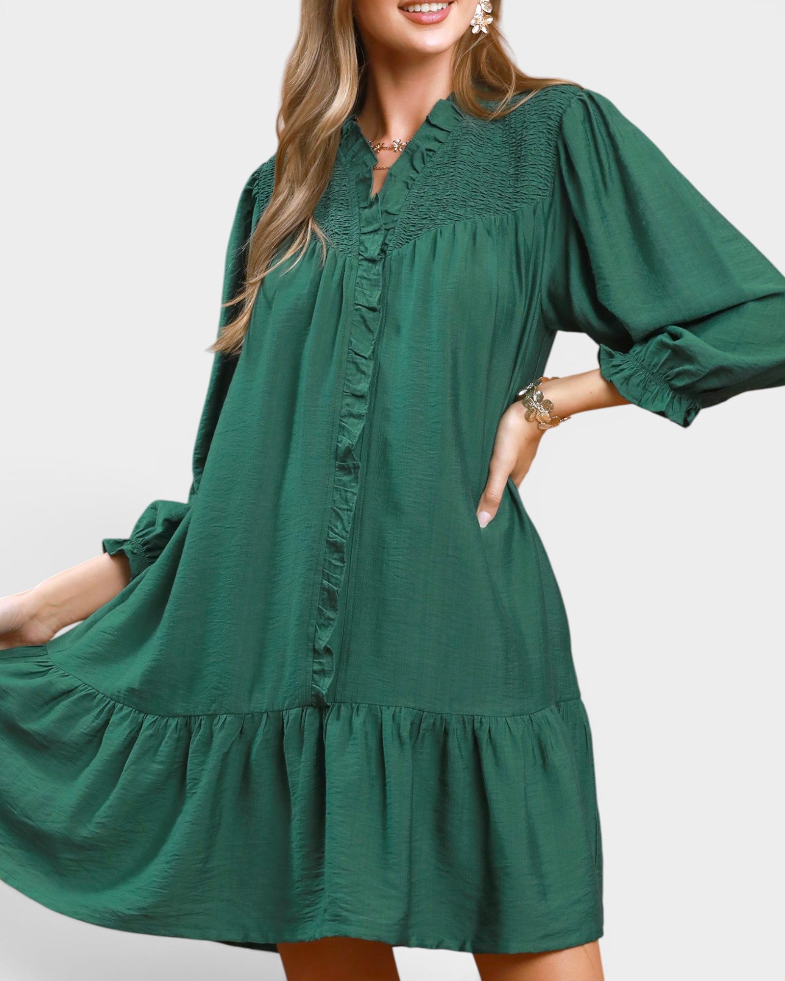 Woman wearing a green dress with long sleeves on a plain background