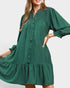 Woman wearing a green dress with long sleeves on a plain background