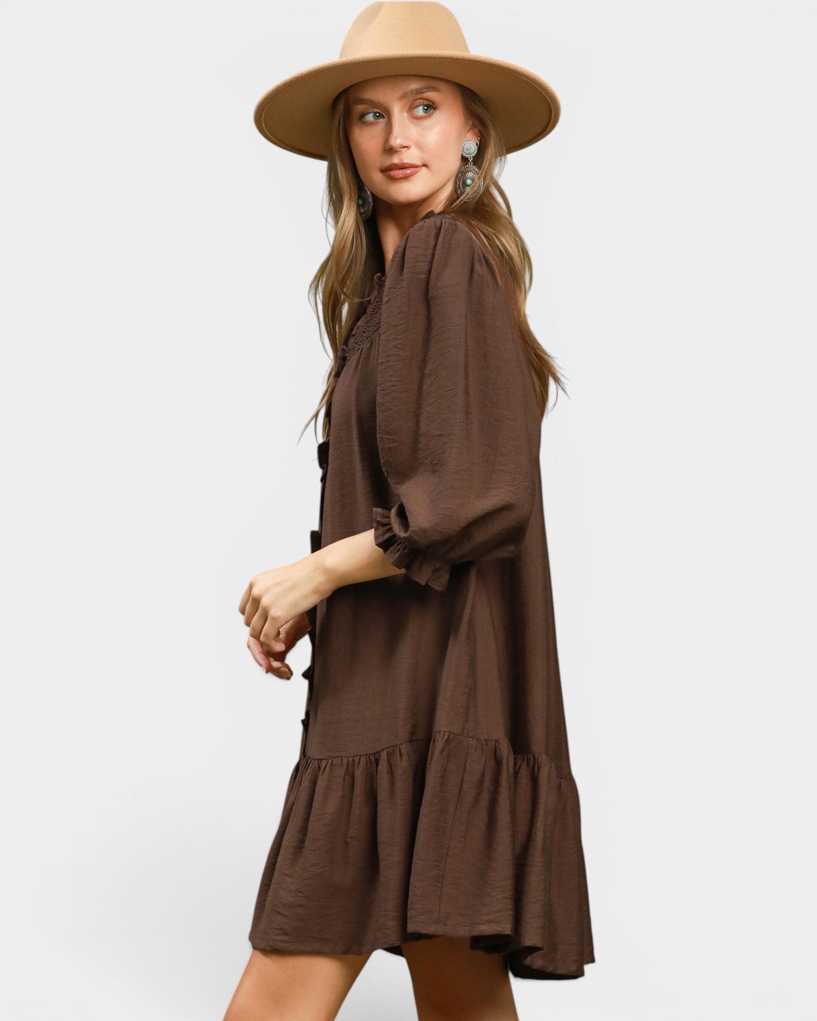 Woman wearing a brown dress and beige hat on a white background