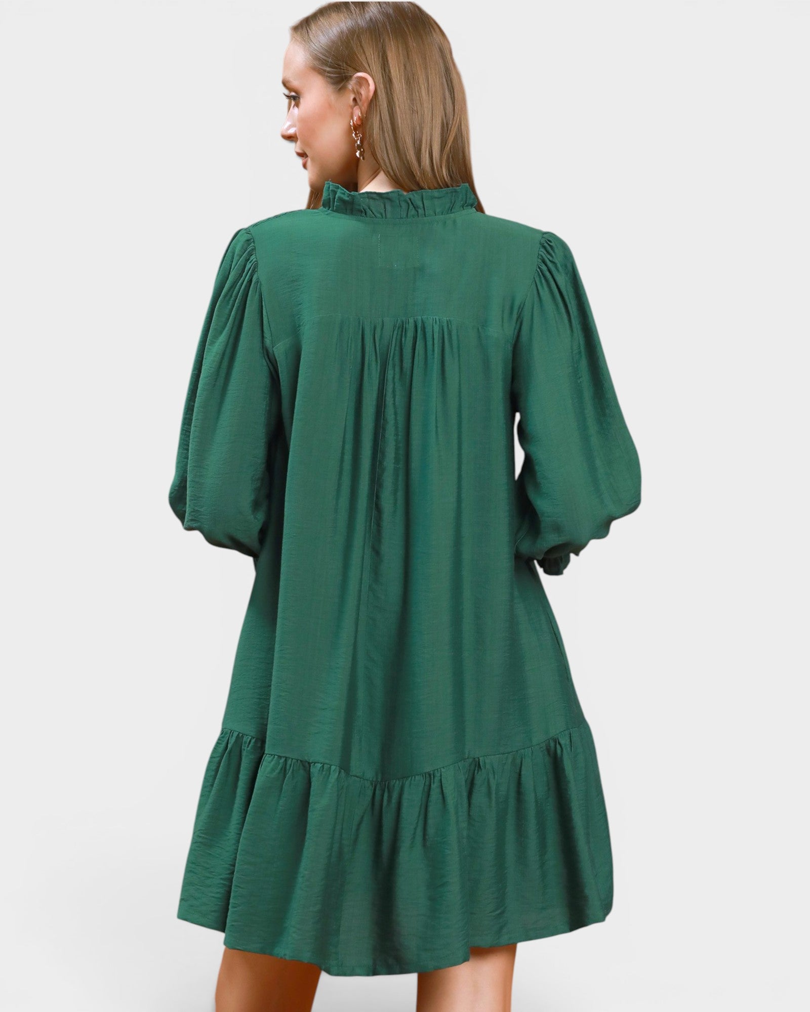 Green dress with long sleeves and ruffled hem on a white background