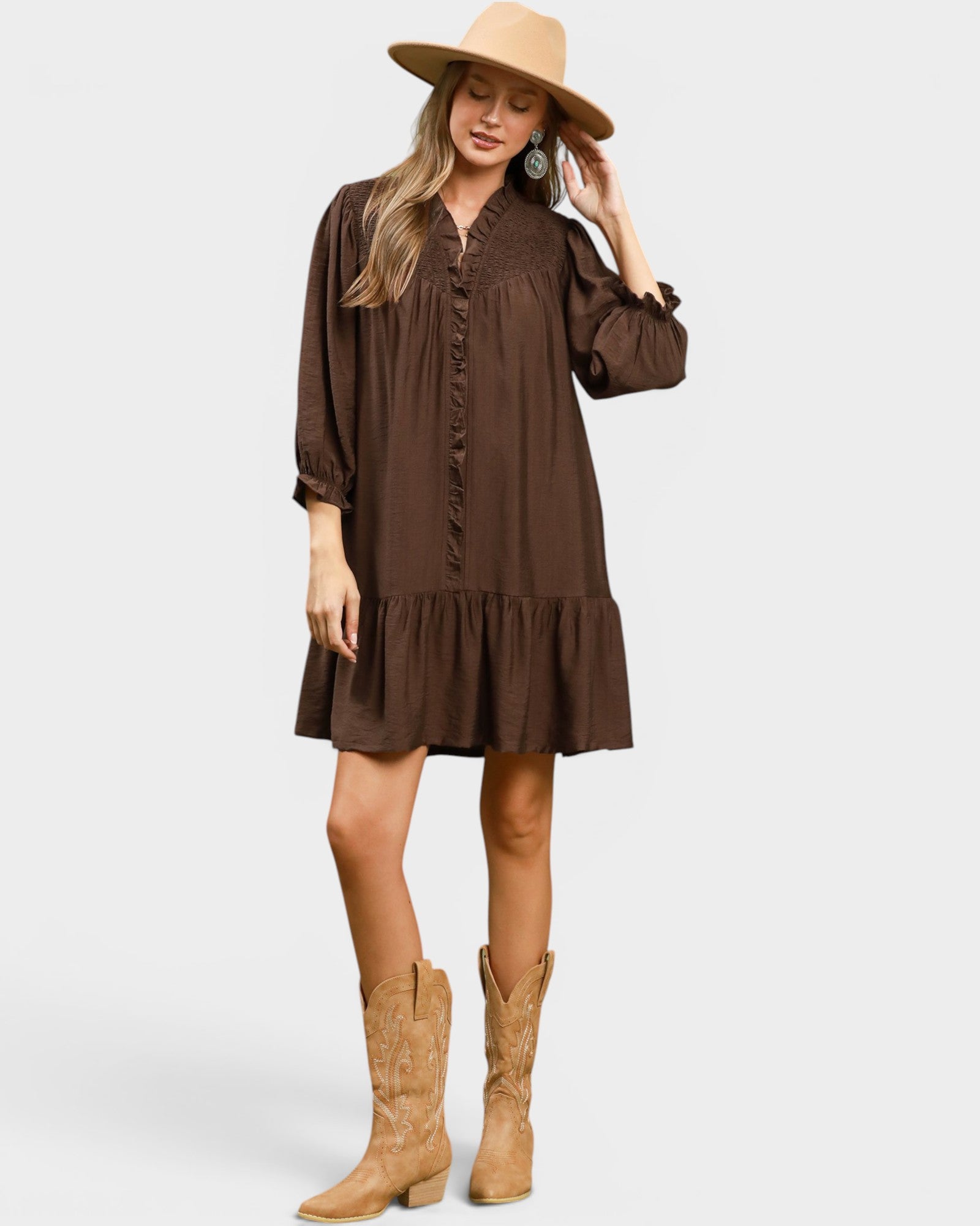 Woman wearing a brown dress and tan boots on a white background