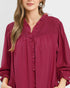 Woman wearing a burgundy dress with smocked neckline and long sleeves on a white background