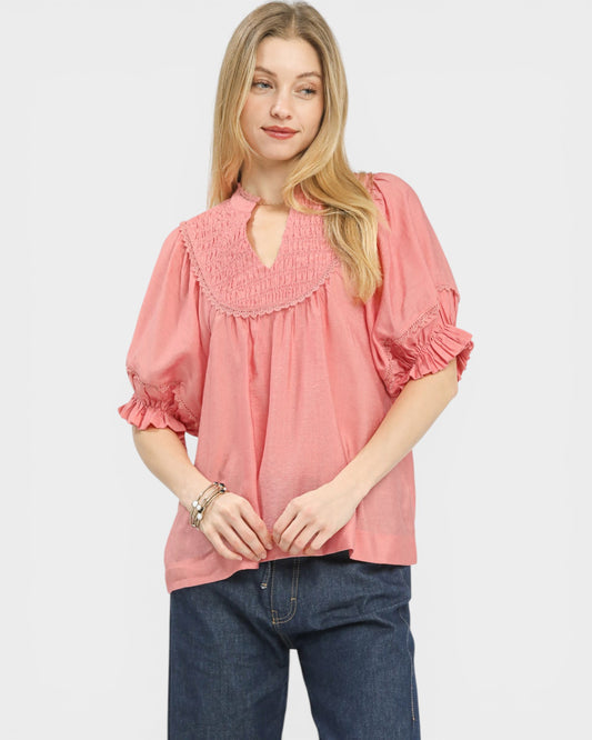 Woman wearing a pink blouse with ruffled details on a white background