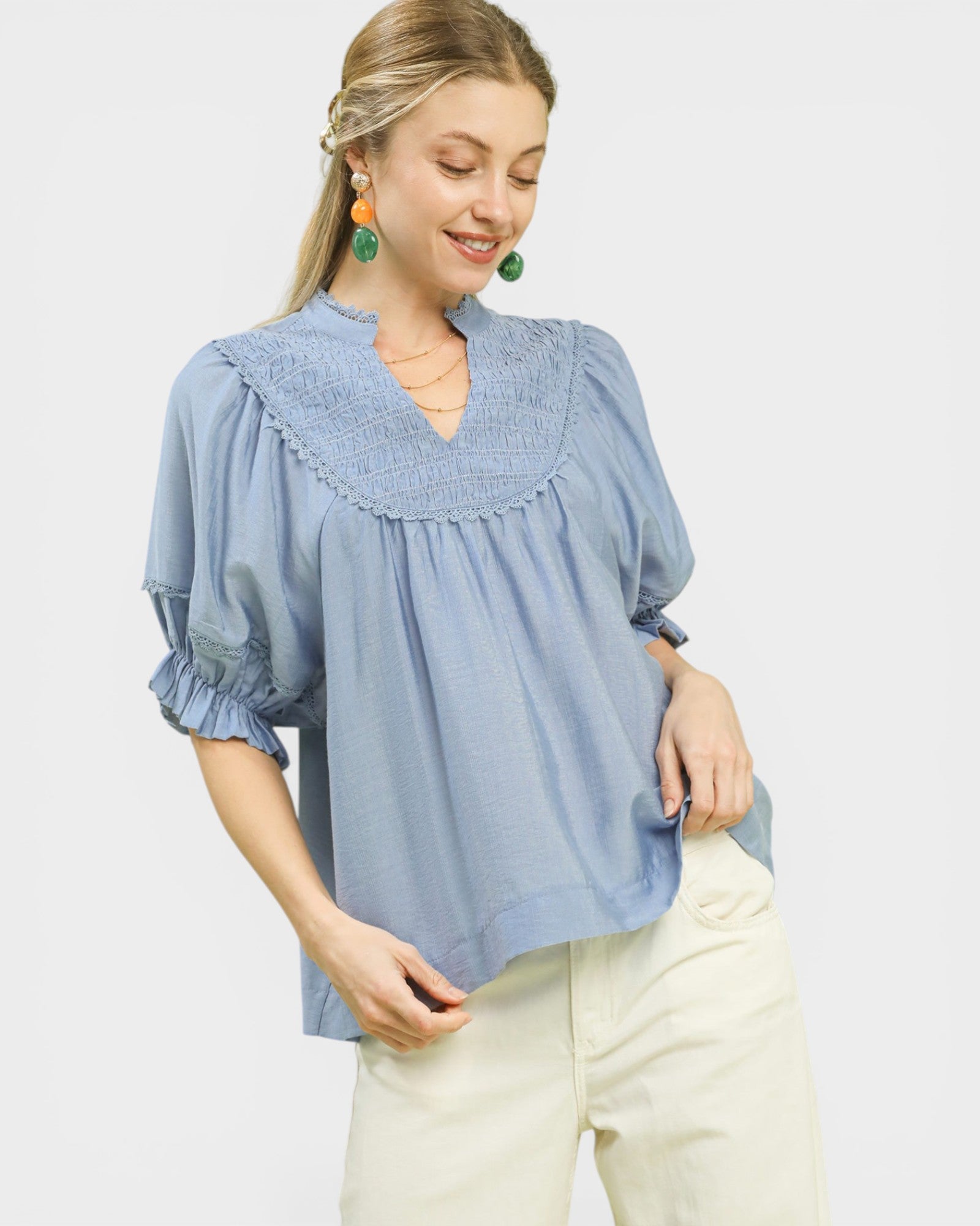 Woman wearing a blue blouse with ruffled details on a light gray background