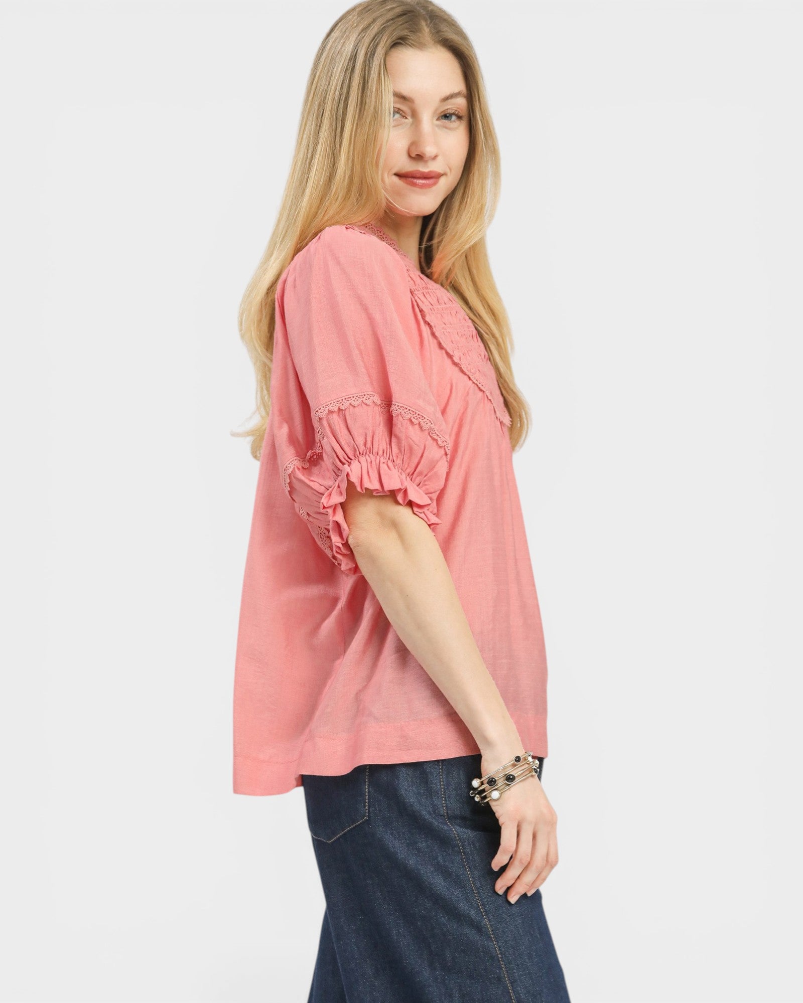 Woman wearing a pink blouse with ruffled sleeves on a white background