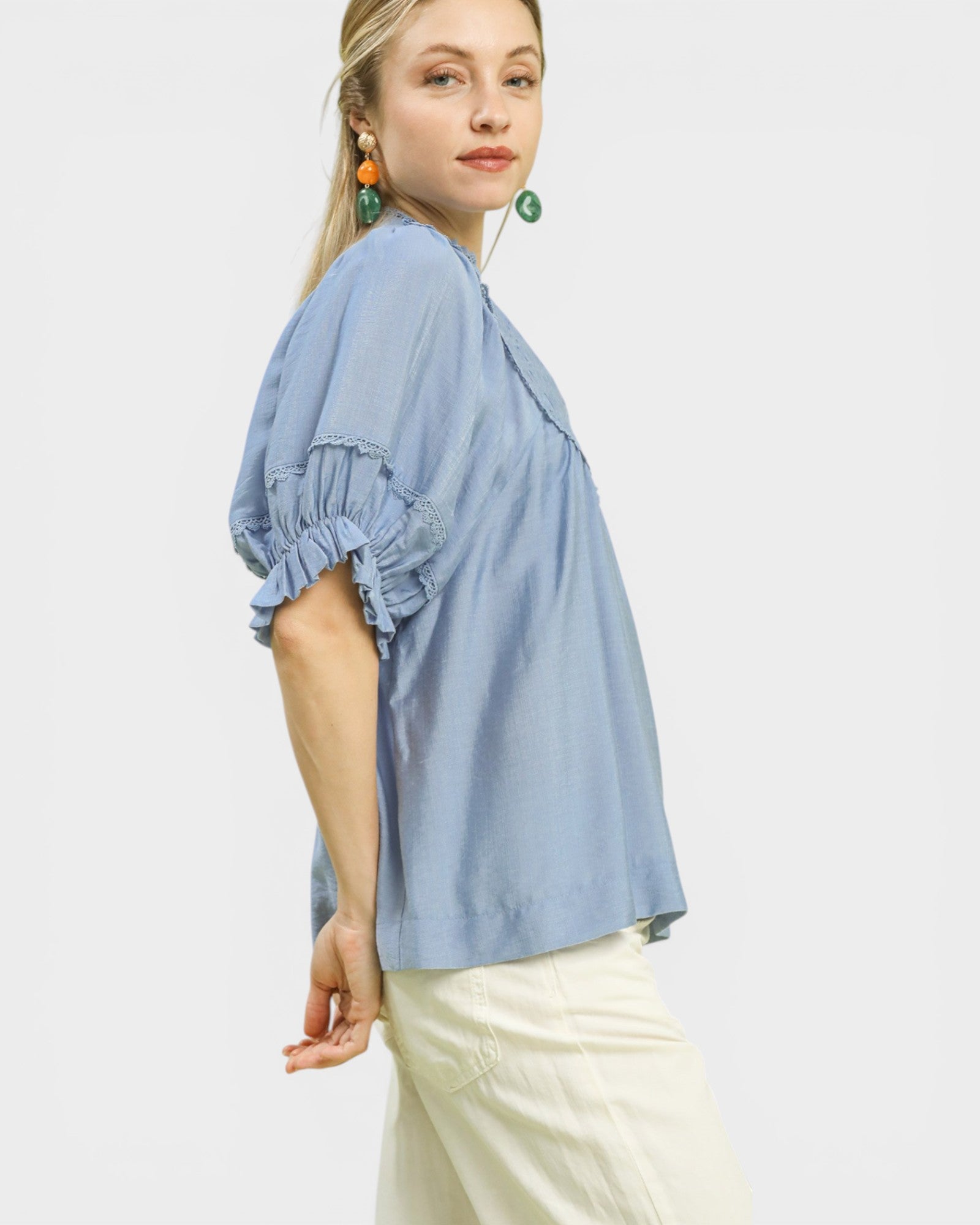 Woman wearing a light blue blouse with ruffled sleeves on a white background