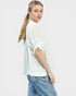 Woman wearing a white blouse and blue jeans with floral embroidery on a light gray background