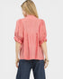 Woman wearing a coral blouse with ruffled sleeves on a white background