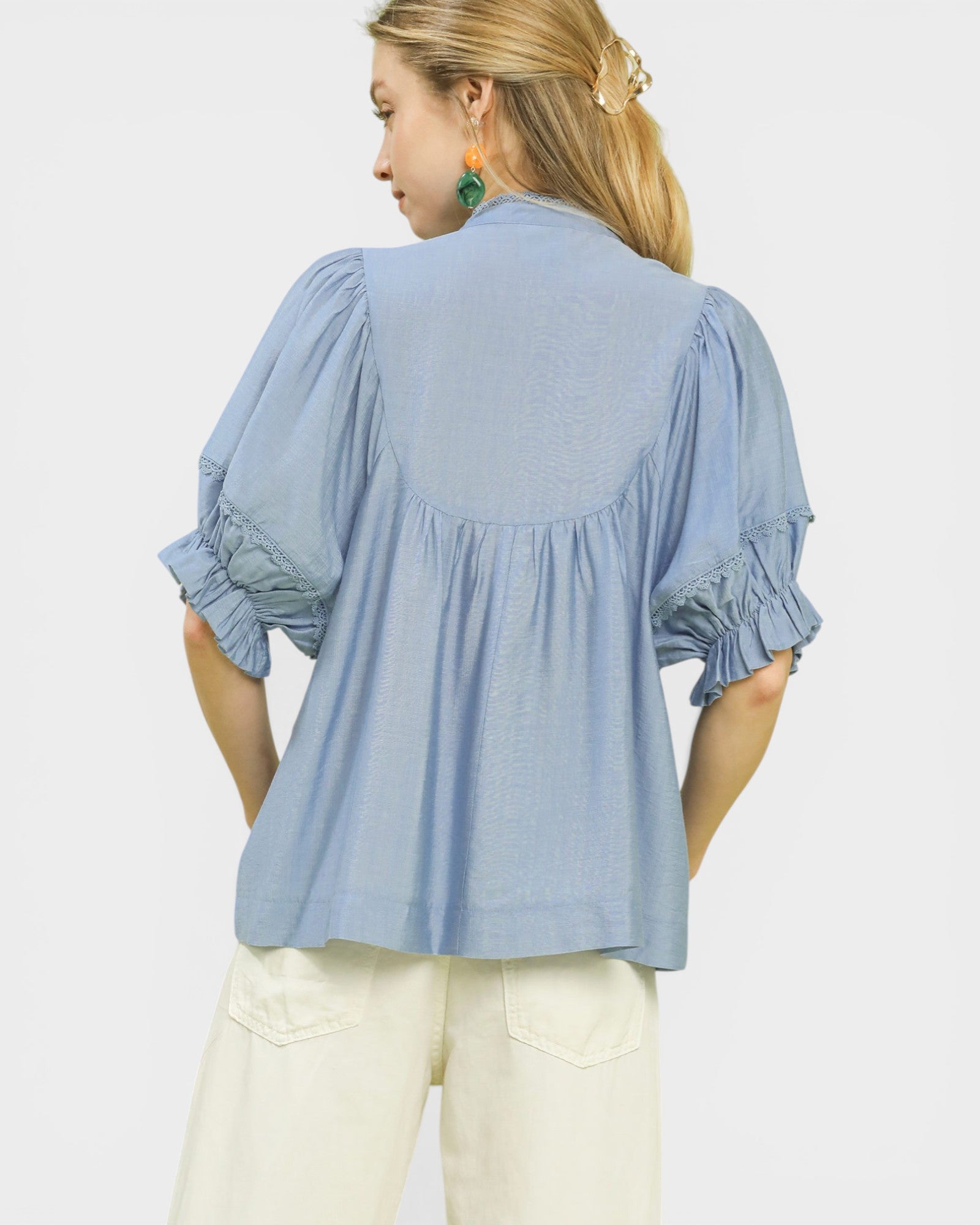 Woman wearing a light blue blouse with ruffled sleeves on a white background
