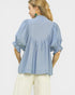 Woman wearing a light blue blouse with ruffled sleeves on a white background