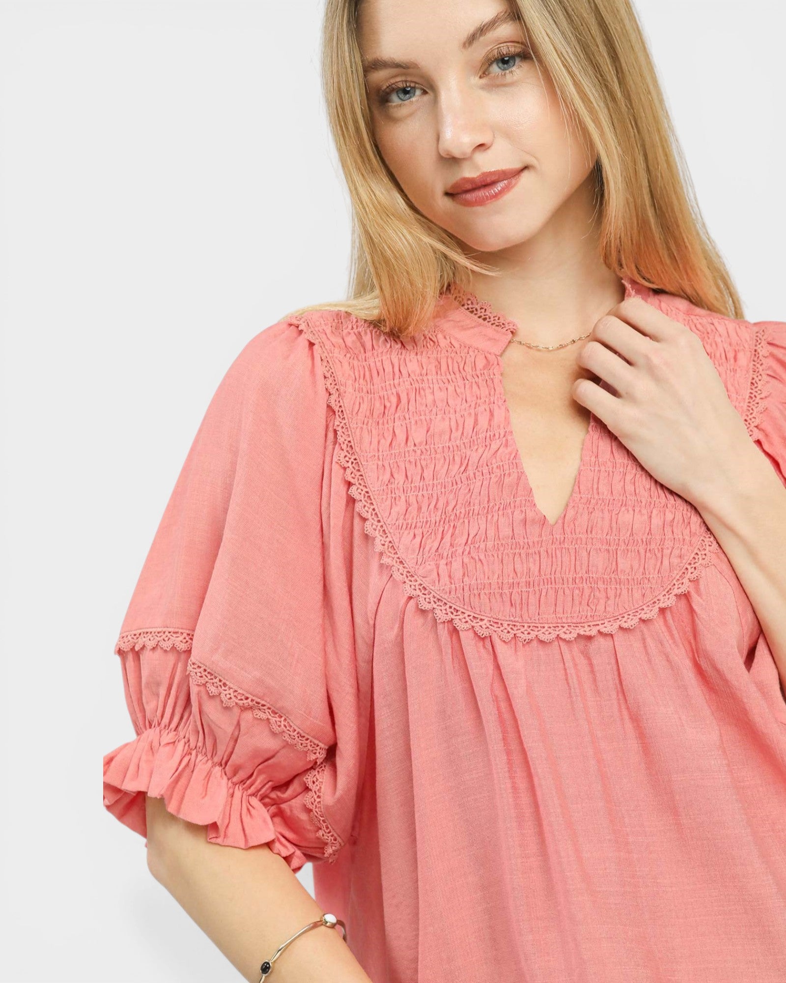 Woman wearing a pink dress with lace details on a white background