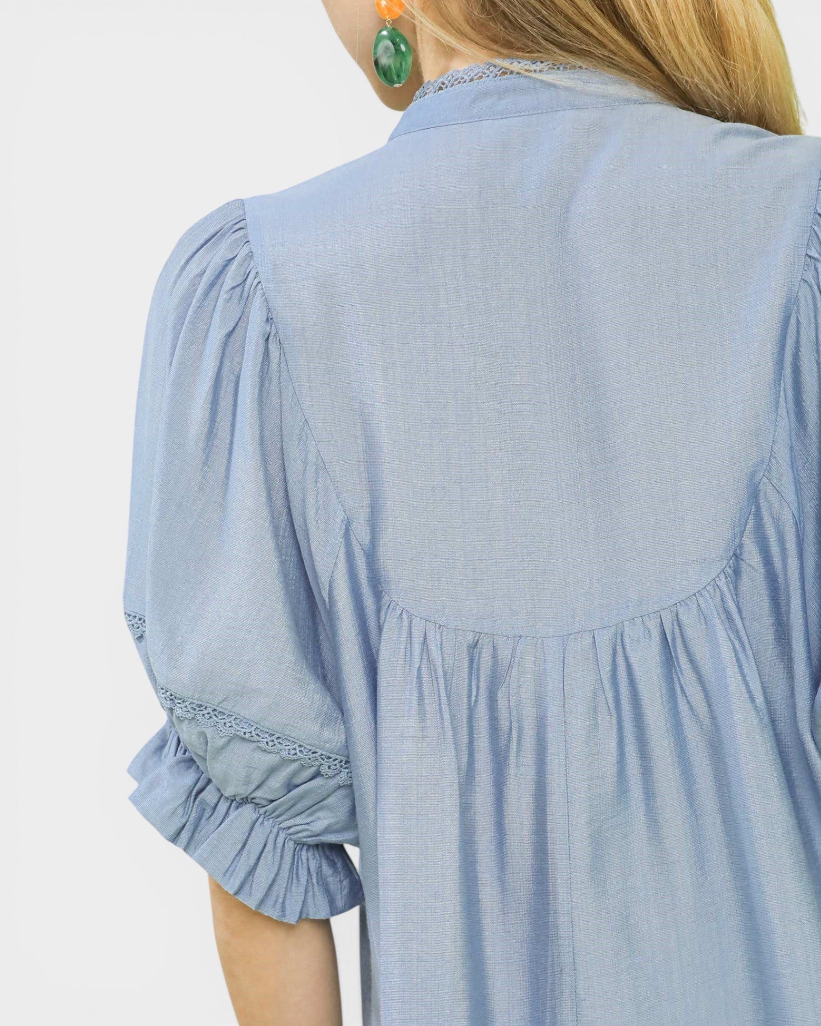 Light blue blouse with ruffled sleeves on a plain background