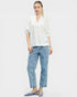 Woman wearing a white blouse and blue jeans with floral embroidery on a white background