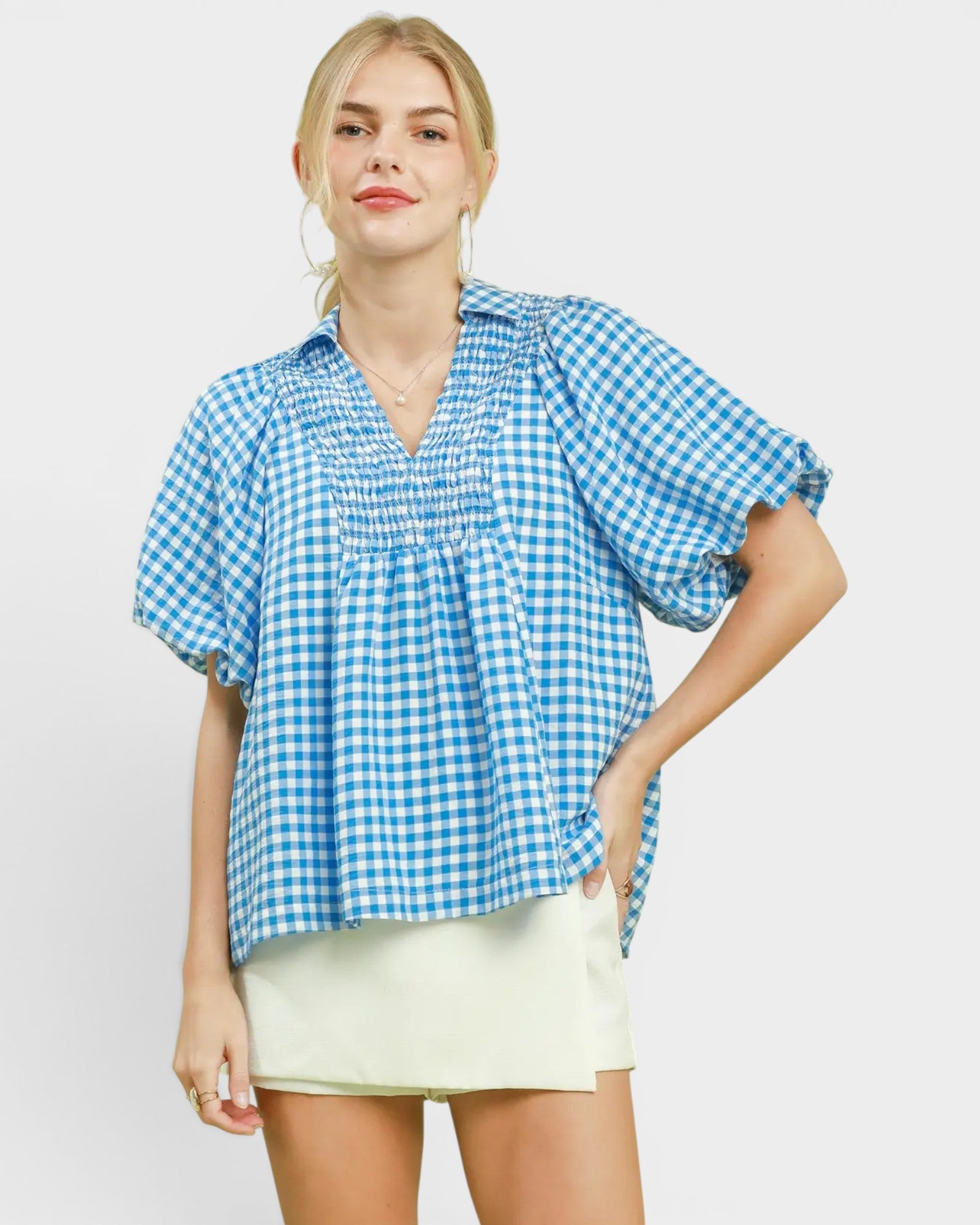 Woman wearing a blue and white checkered blouse with a plain background