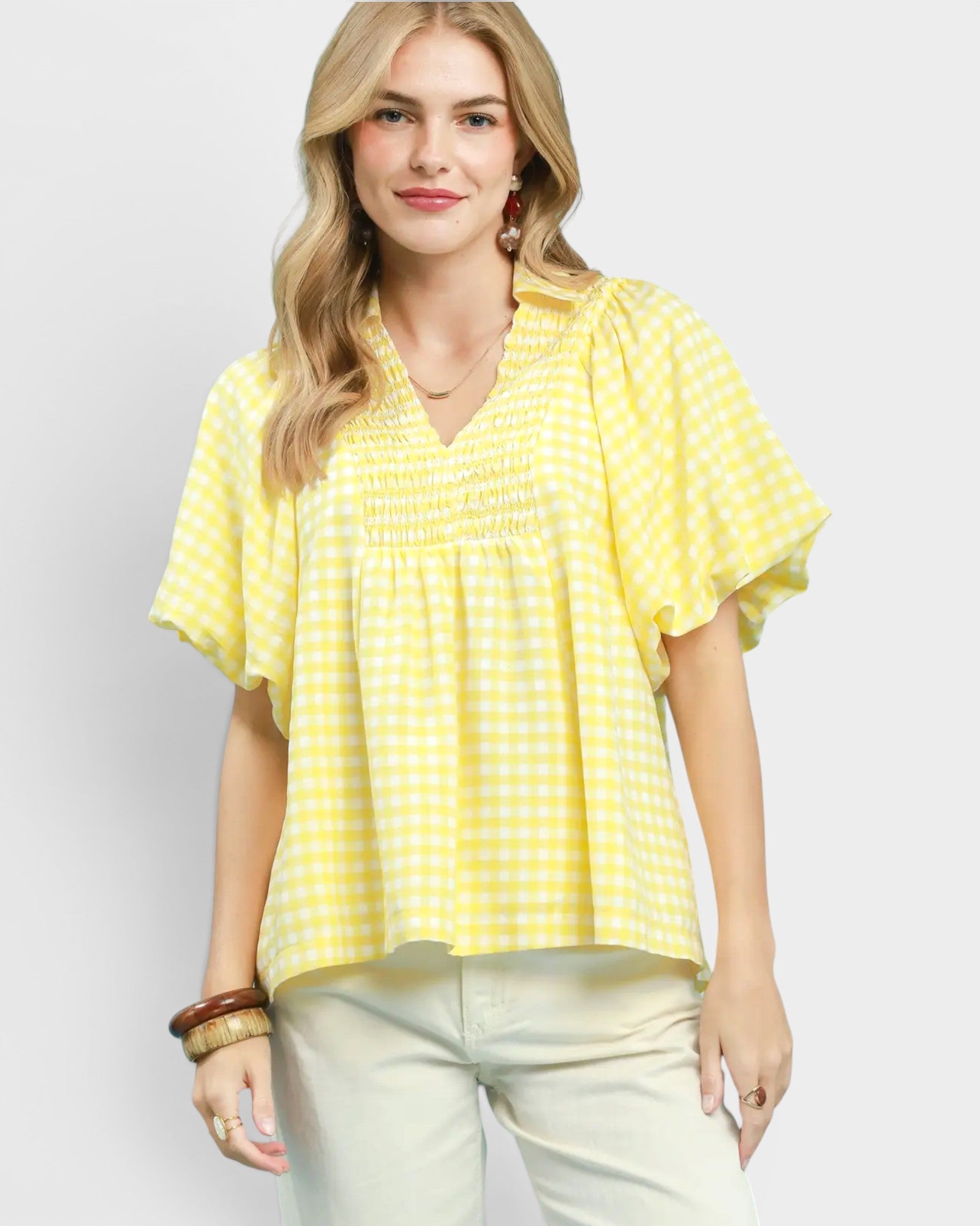 Woman wearing a yellow checkered blouse against a white background