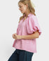 Woman wearing a pink checkered blouse with ruffled sleeves on a white background