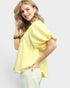 Woman wearing a yellow checkered blouse against a white background