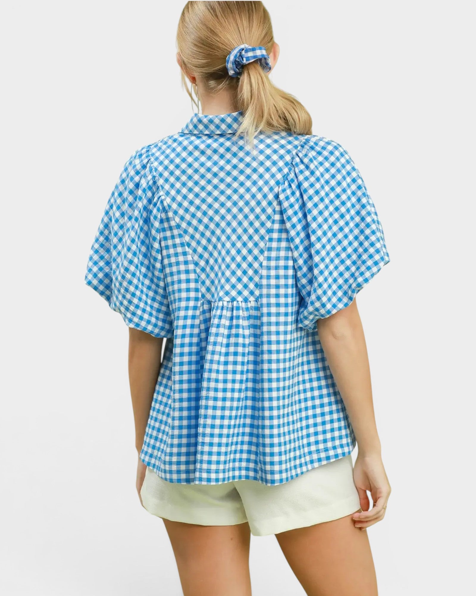 Woman wearing a blue and white checkered blouse on a light gray background